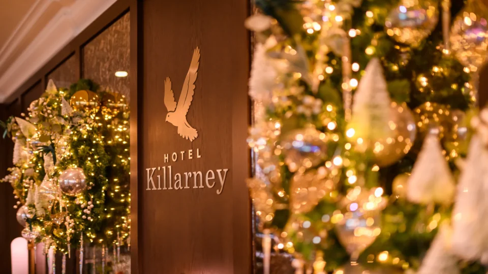 Hotel Killarney entrance decorated with illuminated Christmas wreaths, gold ornaments, and festive lights.