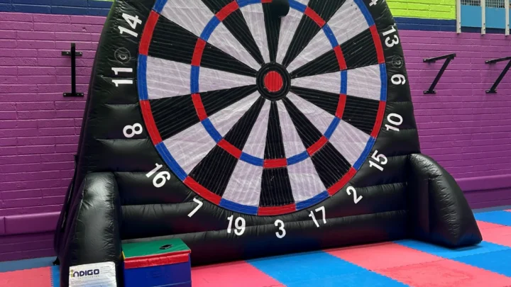 Inflatable darts game in vibrant leisure centre with colourful mats and bright walls, offering fun family-friendly activities.