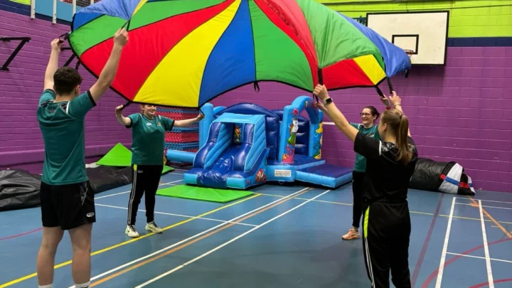Guests enjoy an indoor sports centre with colourful parachute games and inflatable slides, perfect for family fun and activities.