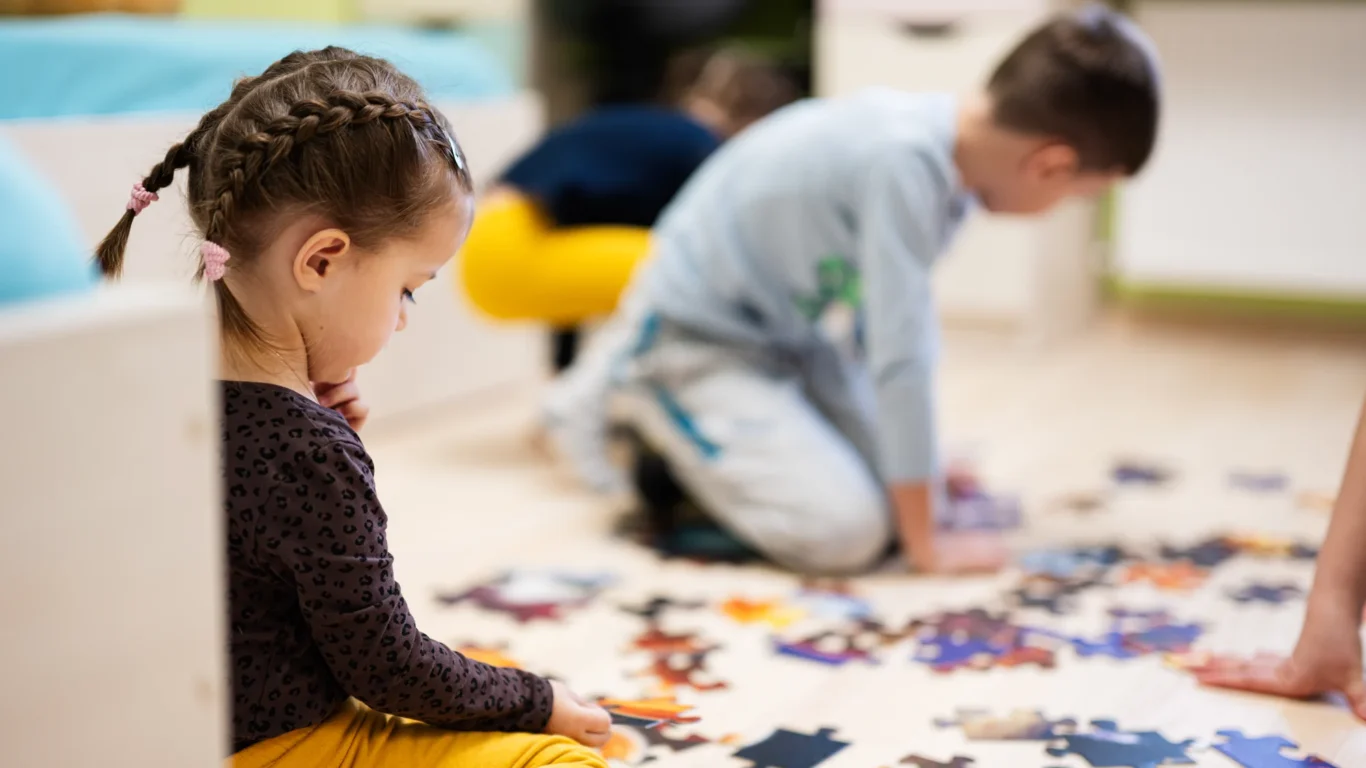 Children enjoy a colourful puzzle in a cosy hotel kids&rsquo; club, ensuring fun and engaging activities for young guests.