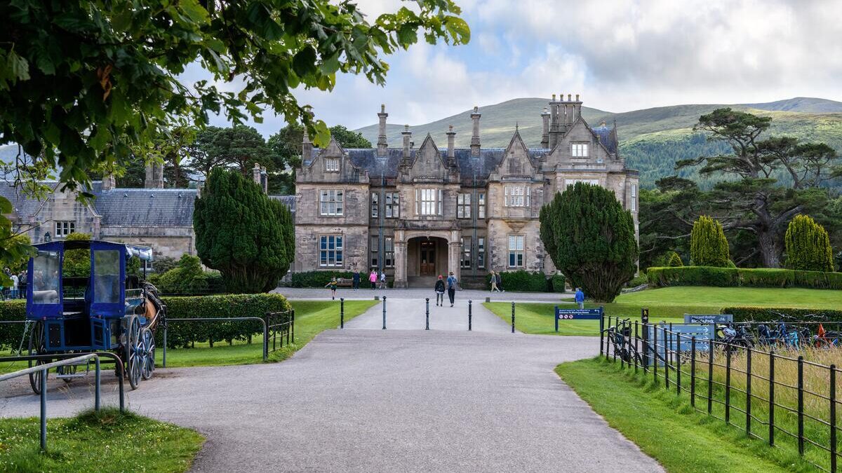 Grand historic hotel facade surrounded by lush gardens and scenic mountains, offering a luxurious, tranquil retreat.